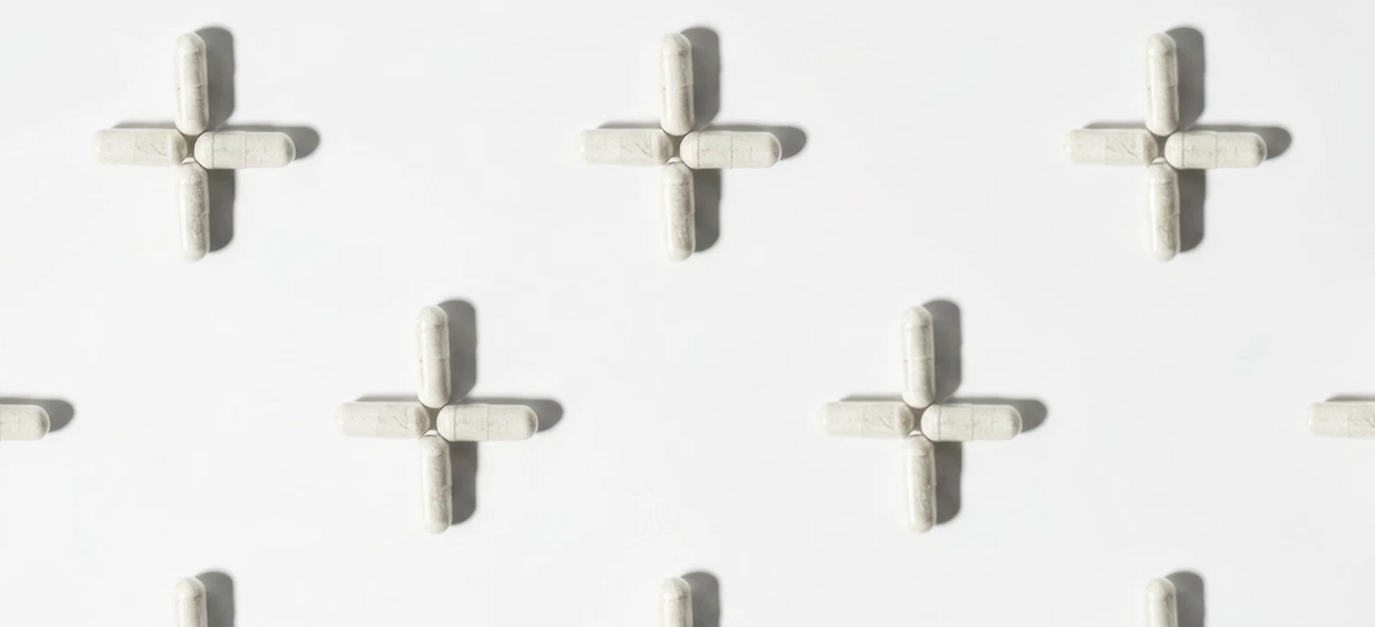 White background with multiple gray plus-shaped pills arranged in a grid pattern.