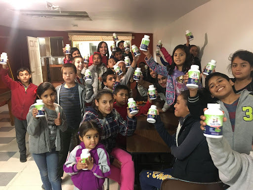 Children at the Estado 29 orphanage hold up their bottles of Previnex Super Vites